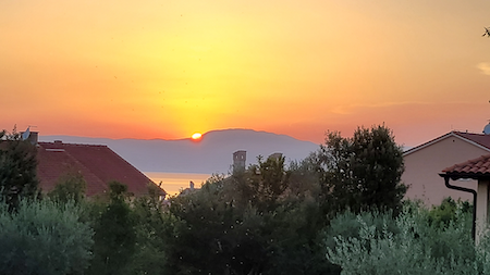 Zdjęcie zachodzącego słońca za wyspami i morzem w Chorwacji